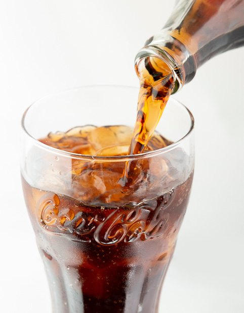 Close-up pack shot of coca-cola being poured into a glass